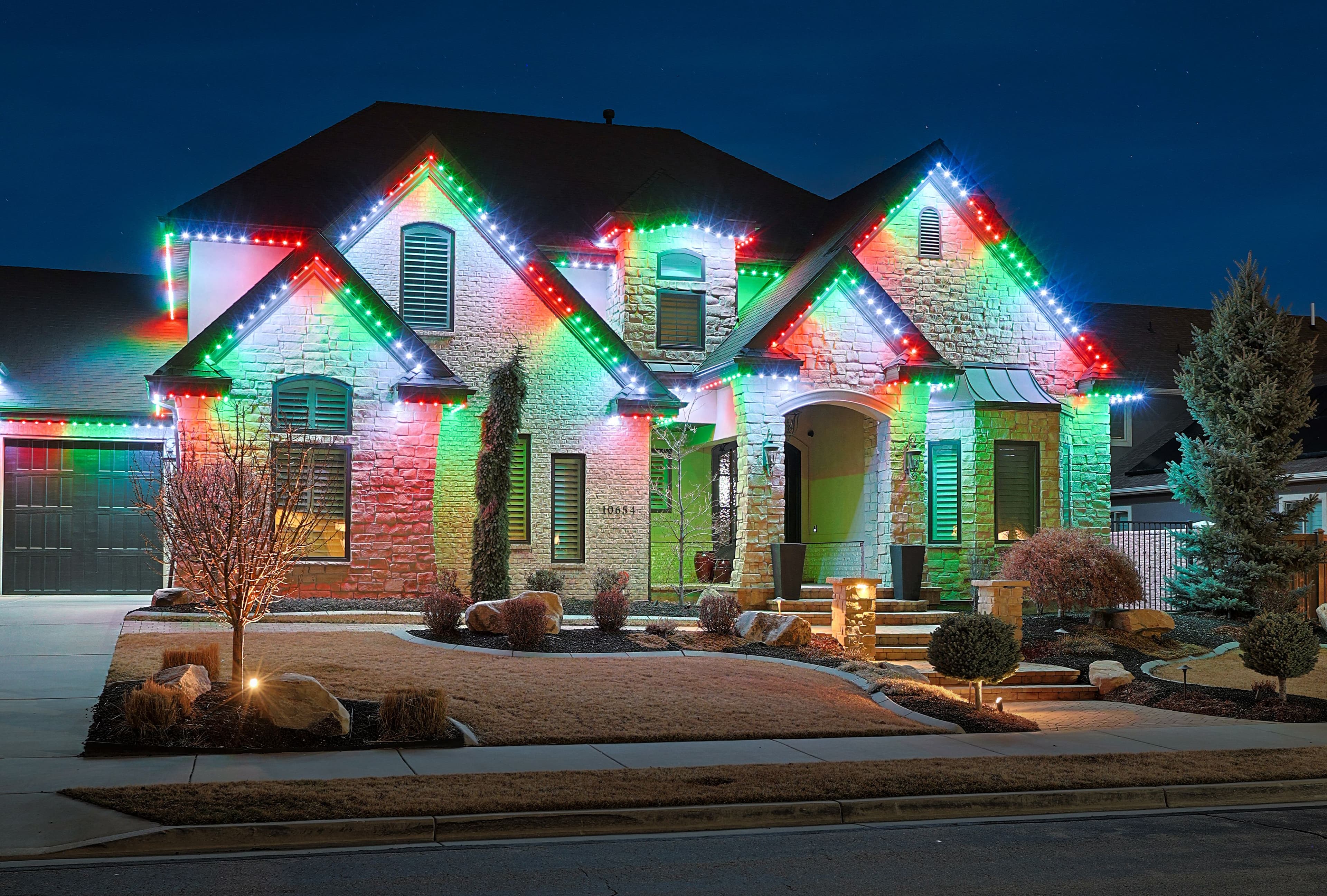 Home illuminated with red, green, and white permanent holiday lighting